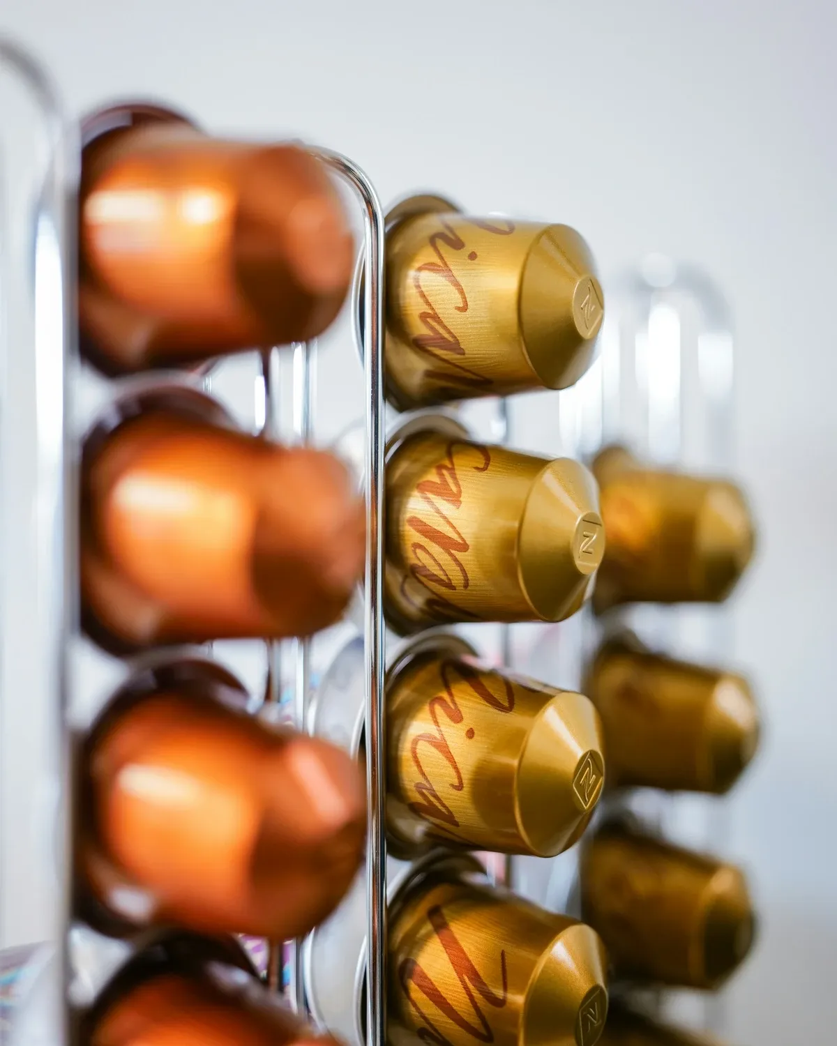 Tall capsule holder filled with copper and gold coffee pods standing upright