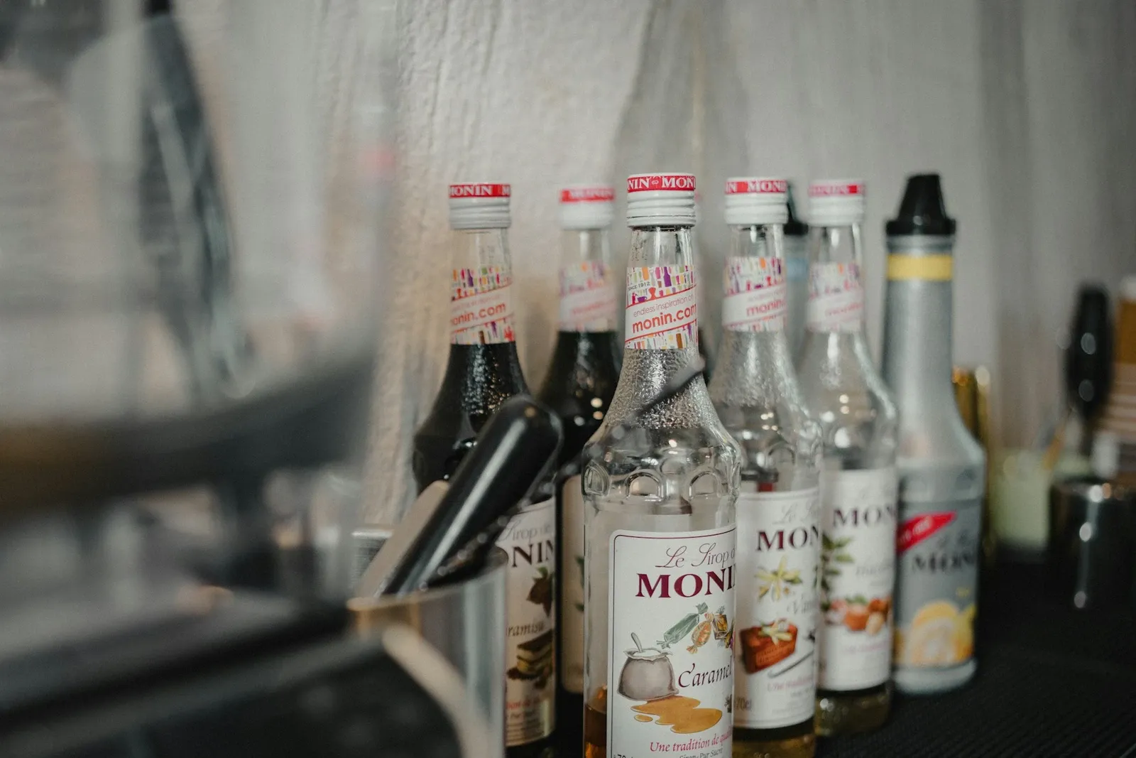 Row of flavored syrup bottles with pumps lined up on a dark counter