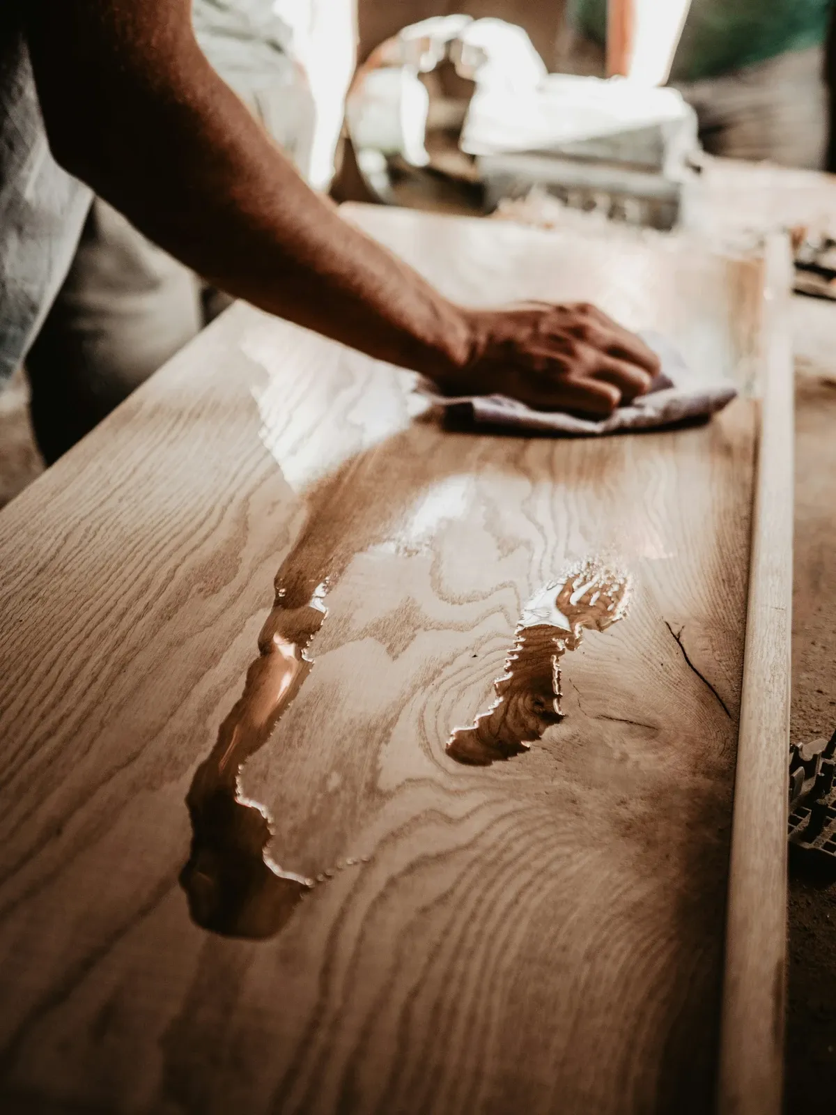 Hand wiping oil finish onto a wood plank for a coffee bar top