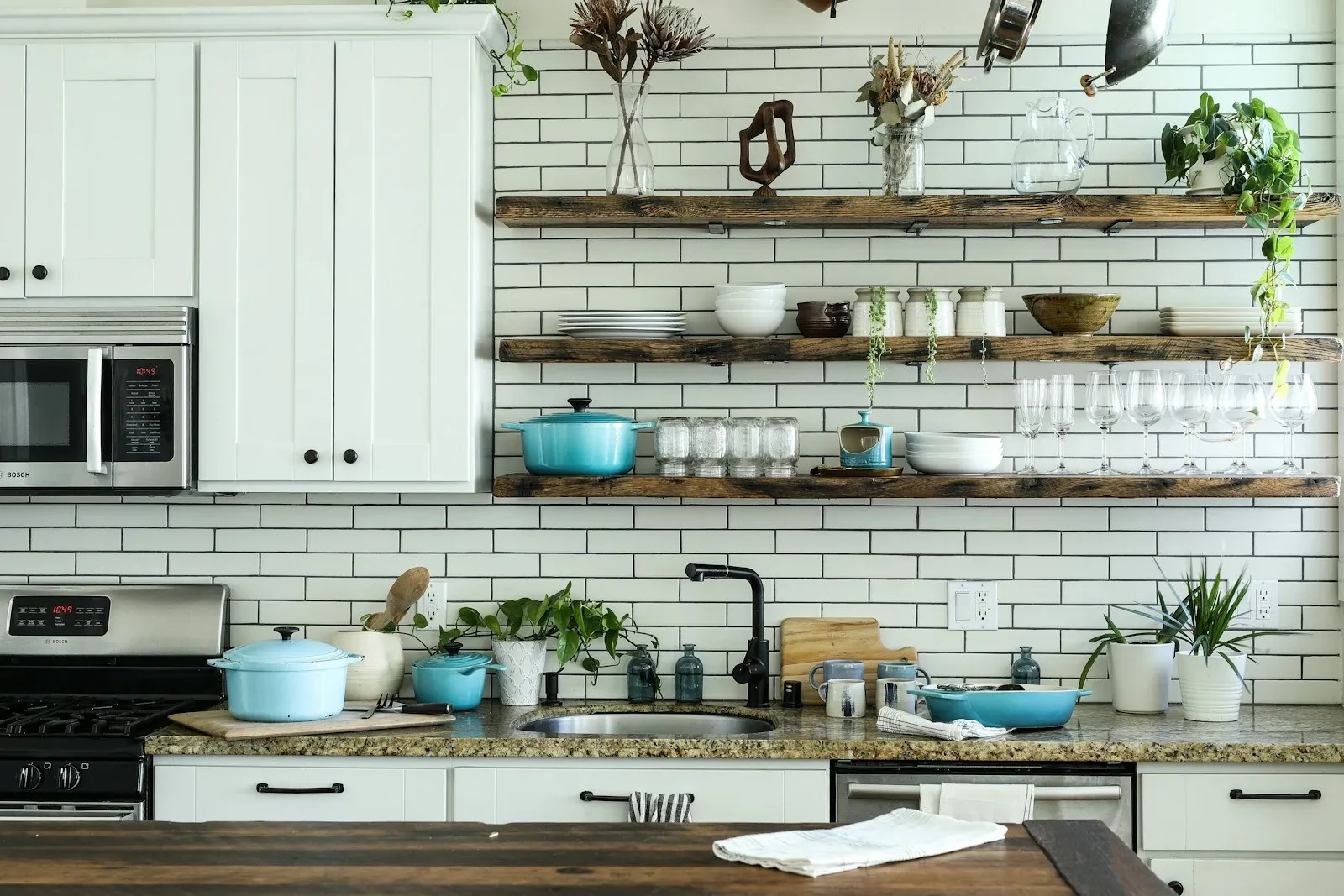 Farmhouse kitchen with open wood shelves of white dishes above a counter and a white subway tile wall