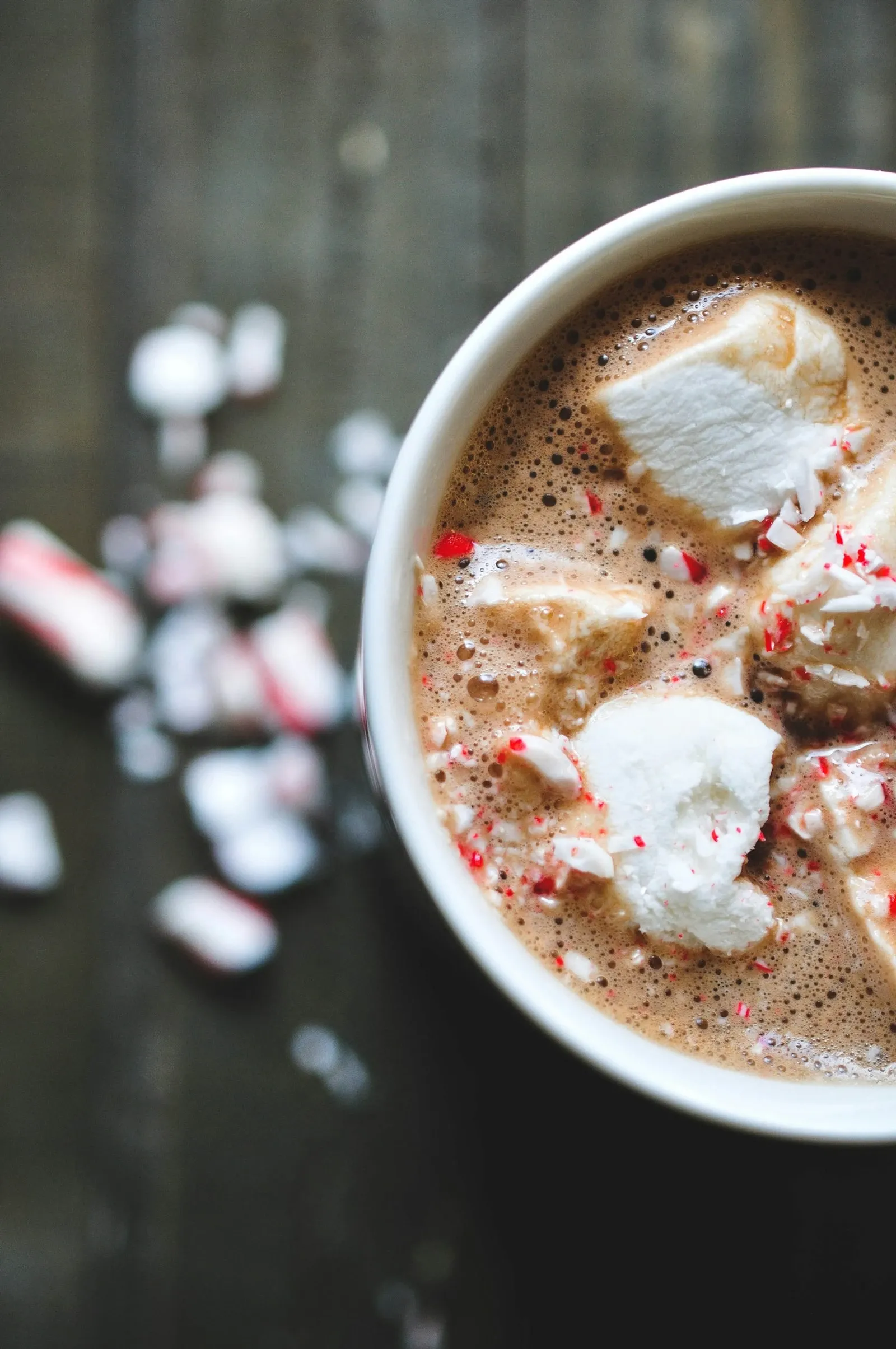 Mug of hot cocoa with mini marshmallows and two candy canes seen from above