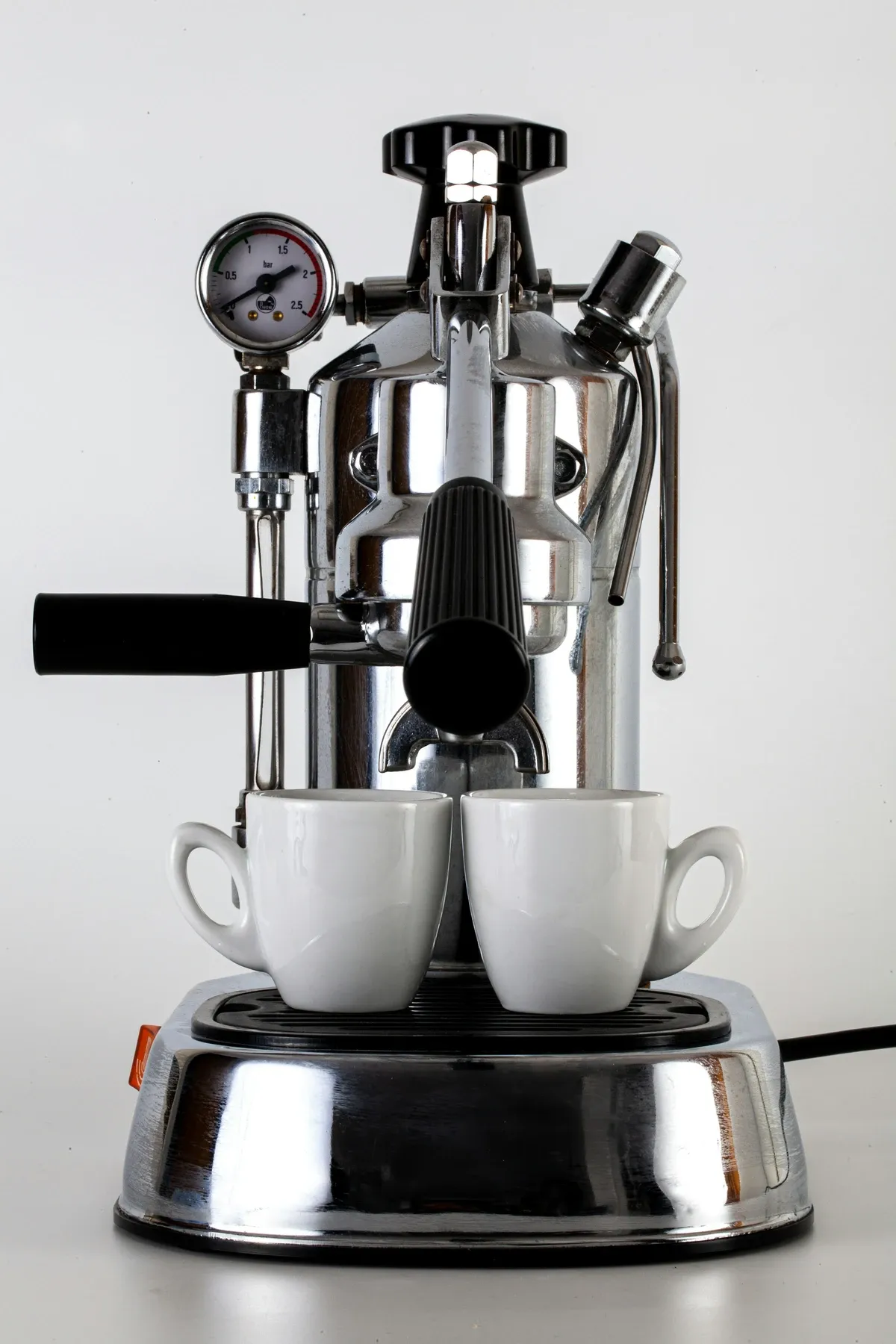 Chrome lever espresso machine with a pressure gauge and wood handle pulling into two white cups