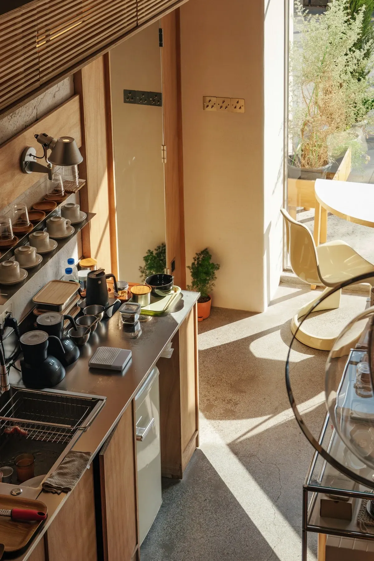 Narrow counter coffee station with a coffee maker, labeled jars and a tray of supplies in a neat row