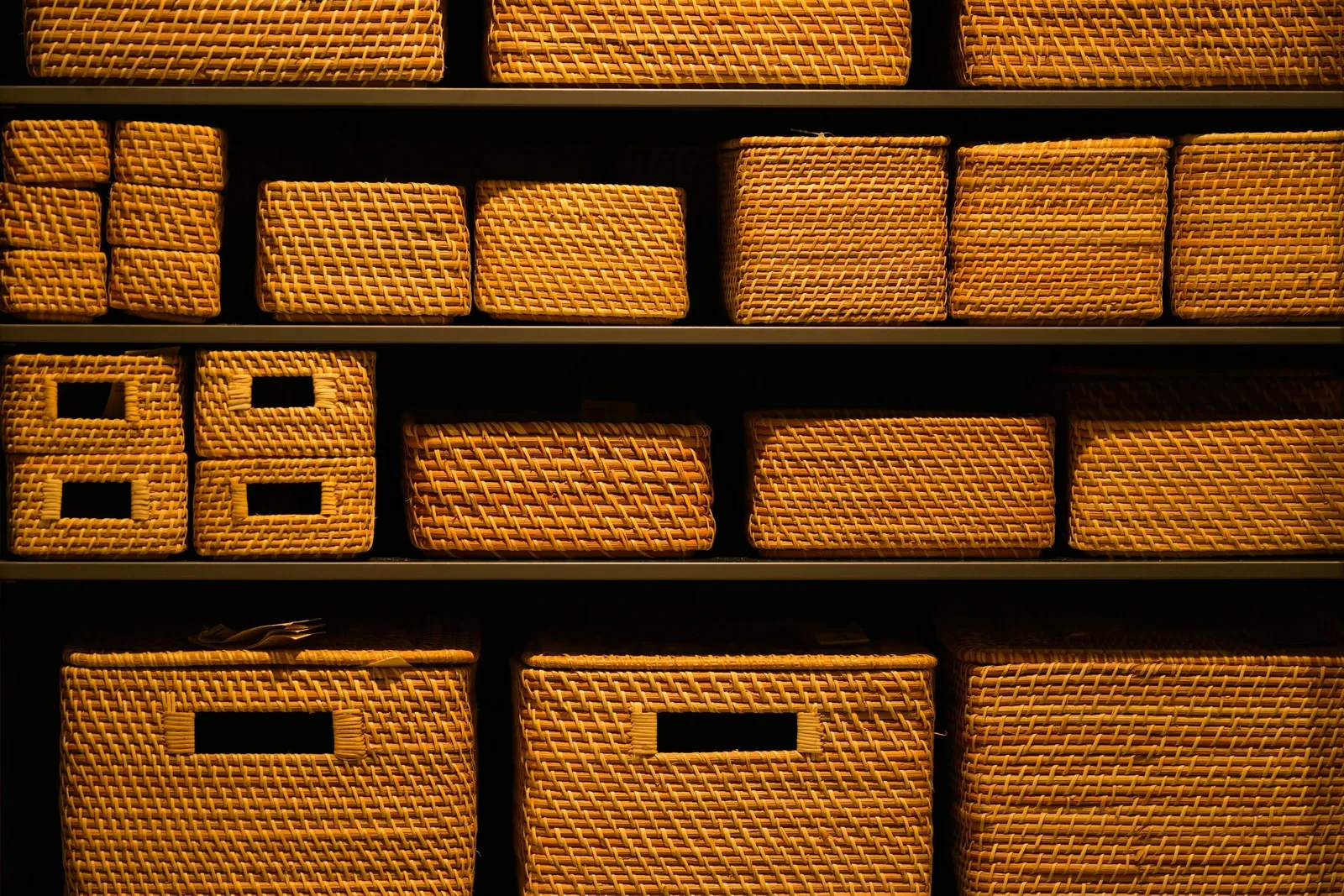 Dark shelves filled with rows of woven storage baskets in different sizes